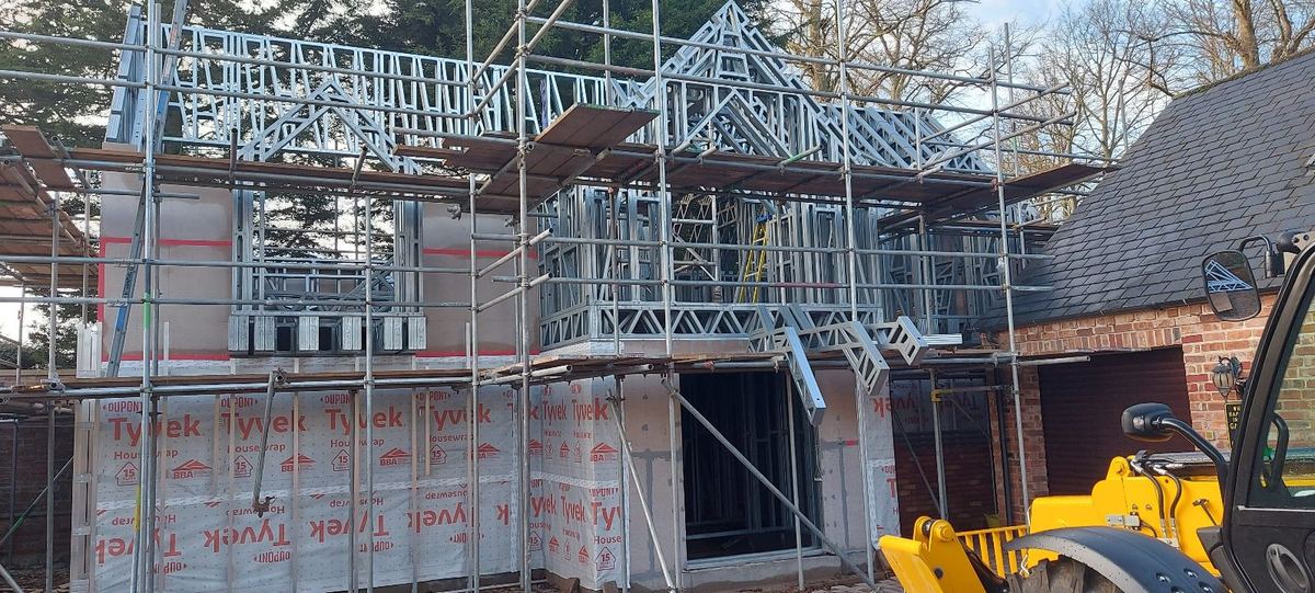 The house frame wrapped in a waterproof membrane behind scaffolding